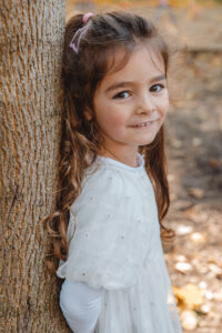 kind steht am baum und lacht